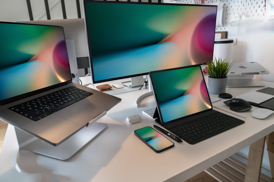 A contemporary workspace featuring a laptop, tablet, smartphone, and monitor displaying abstract backgrounds.