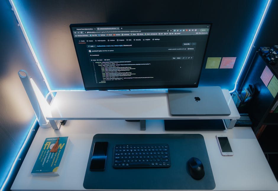 A minimalist workspace with a computer setup, gadgets, and neon lighting for a sleek modern look.